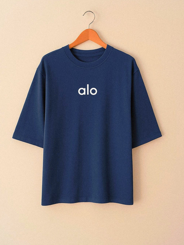 تیشرت زنانه رنگ سورمهای با نوشتهی کوچک alo روی سینه، آستین تا پایین آرنج، چیدهشده روی زمینهی ساده