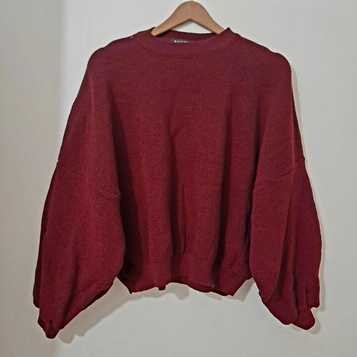 بافت لش زنانه زرشکی، آزاد و راحت، با آستین بادکنکی و یقه گرد، مناسب زمستان، روی چوبلباسی سفید، جزئیات بافت واضح و رنگ واقعی